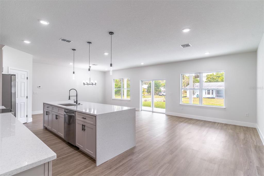 A modern kitchen with a large quartz island overlooks an open-concept living area with windows — 983 PACE DRIVE NW, PALM BAY, FL