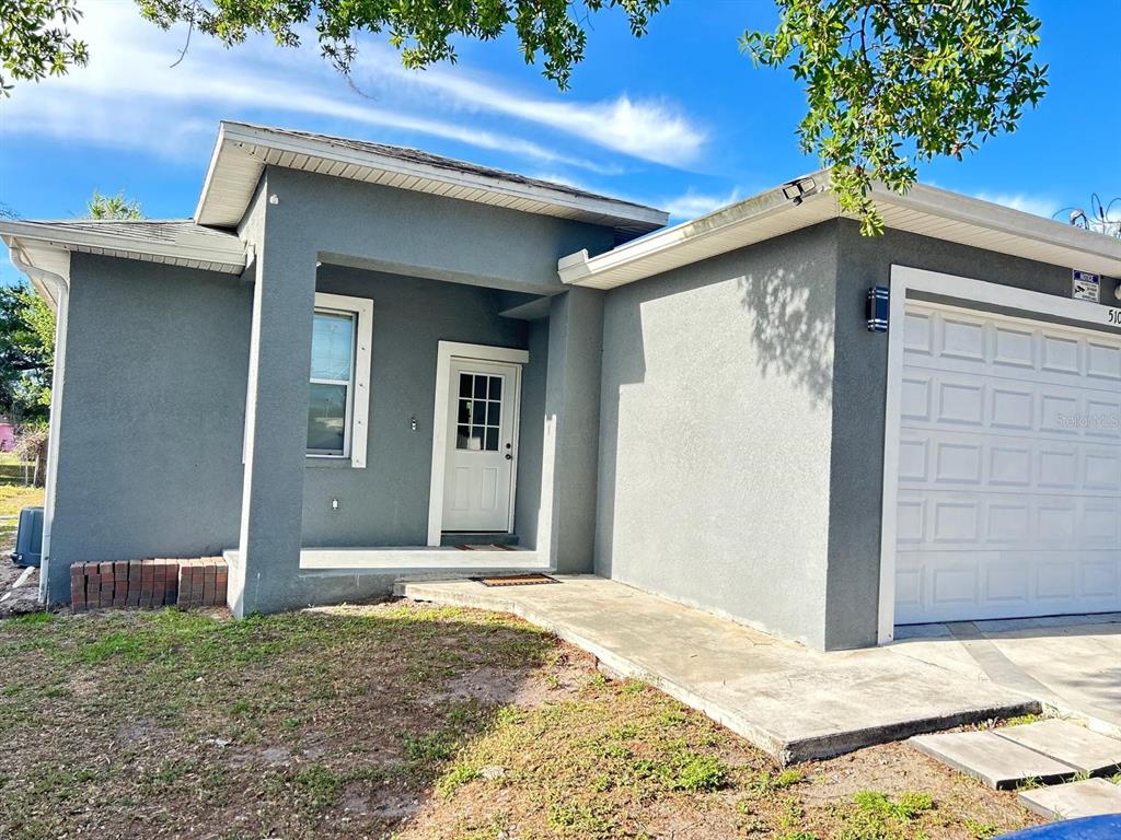 A gray stucco house with a white front door and a single-car garage — 5103 E 18TH AVENUE, TAMPA, FL