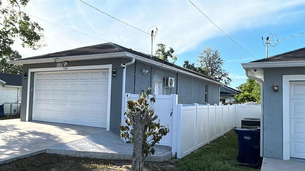 An exterior view of a detached garage with a white door and a vinyl fence — 5103 E 18TH AVENUE, TAMPA, FL