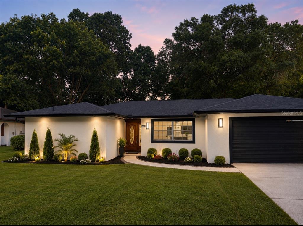 A single-story house with white stucco walls, a black roof, and a black garage door — 436 BISON CIRCLE, APOPKA, FL