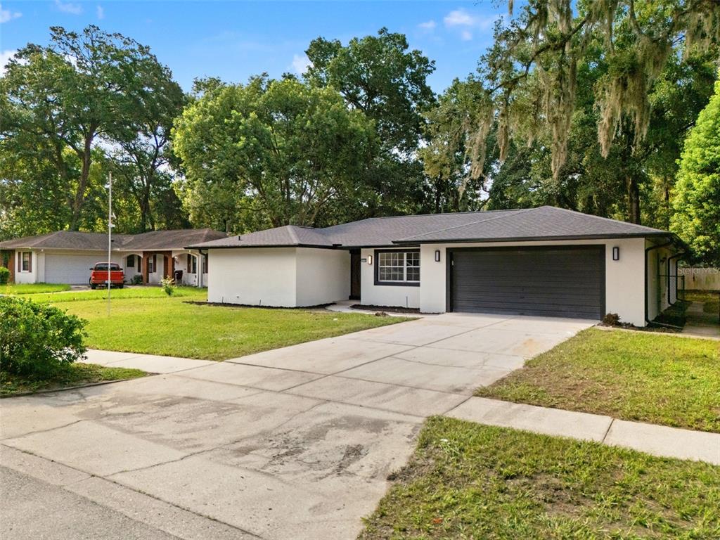 A single-story house with a white exterior, dark garage door, and a concrete driveway — 436 BISON CIRCLE, APOPKA, FL