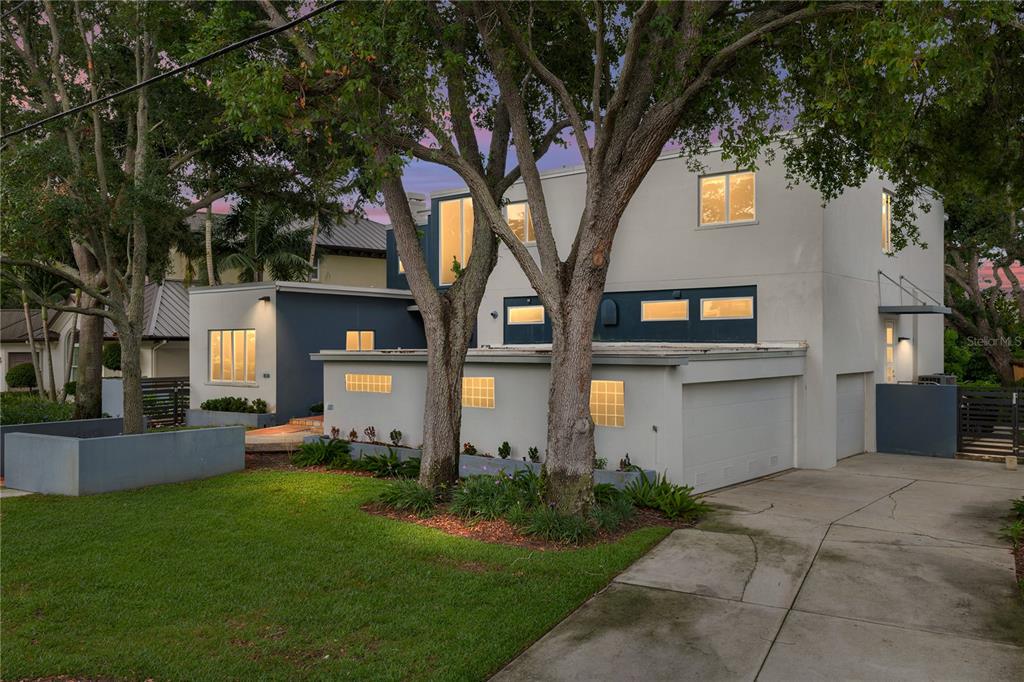 A two-story modern house with a garage, glass block windows, and mature trees in front — 838 MONTEREY BOULEVARD NE, ST PETERSBURG, FL