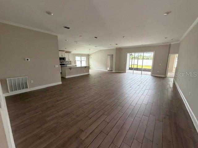An open-concept living area features wood-look tile flooring, a kitchen island, and sliding glass doors — 34 GYPSUM PLACE, ST AUGUSTINE, FL