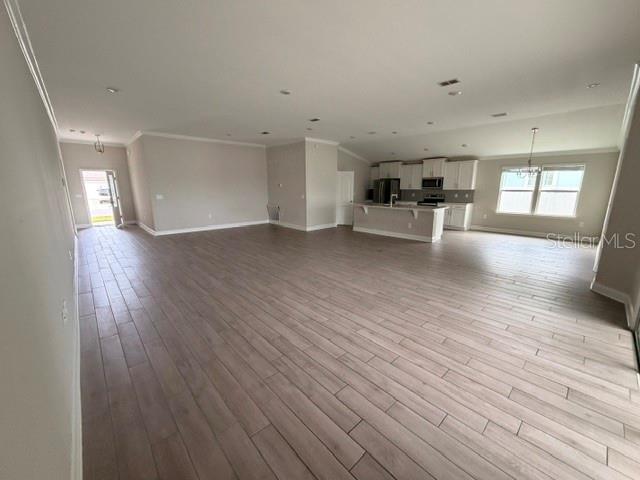An open-concept living area features light wood-look tile flooring and a kitchen with white cabinetry — 34 GYPSUM PLACE, ST AUGUSTINE, FL
