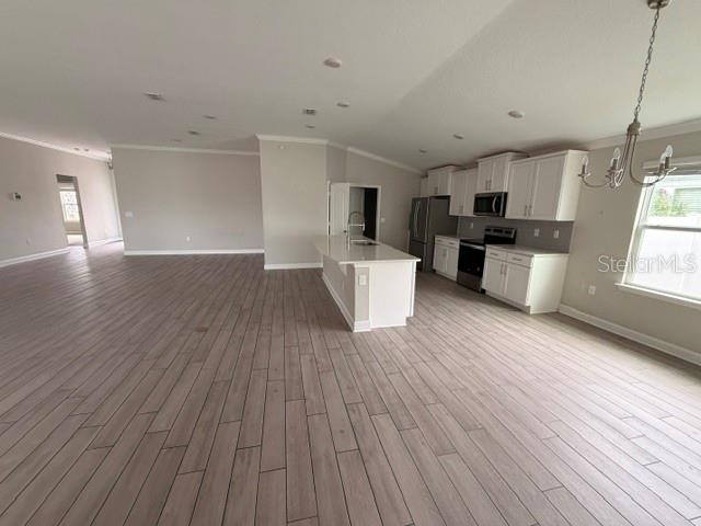 An open-concept kitchen features white cabinets, a central island, and light-colored wood-look tile flooring — 34 GYPSUM PLACE, ST AUGUSTINE, FL
