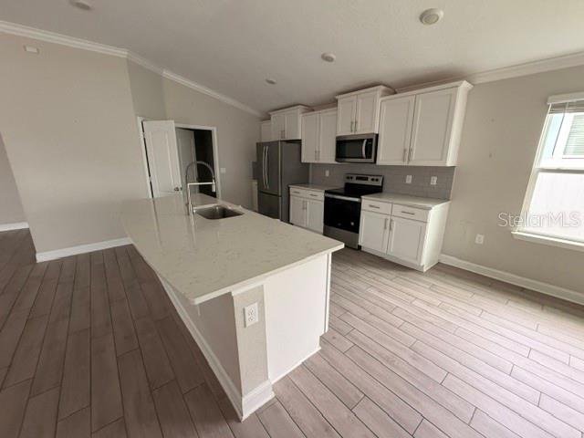 A kitchen features white cabinets, stainless steel appliances, a center island, and wood-look tile flooring — 34 GYPSUM PLACE, ST AUGUSTINE, FL