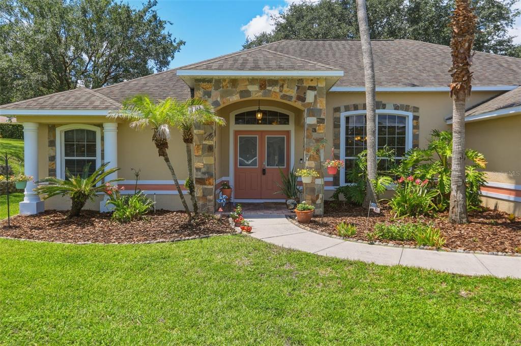 A single-story house with a stone-accented entryway, double front doors, and landscaped front yard — 11340 ALAMEDA SANDRA DRIVE, CLERMONT, FL
