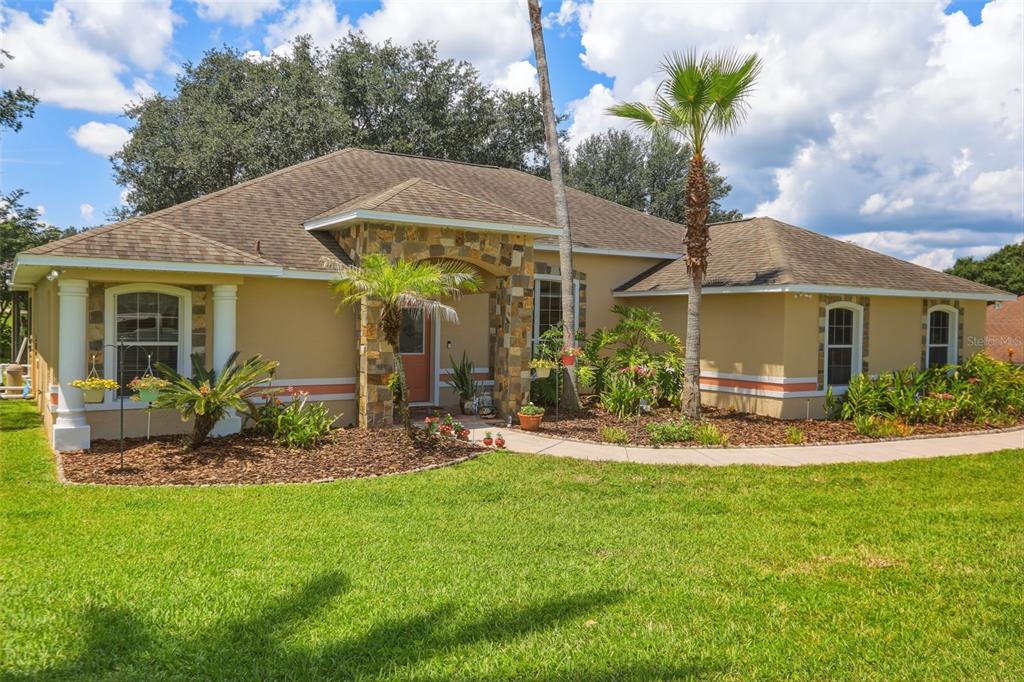 A single-story house with a stone-accented entryway, tan stucco walls, and a palm tree — 11340 ALAMEDA SANDRA DRIVE, CLERMONT, FL