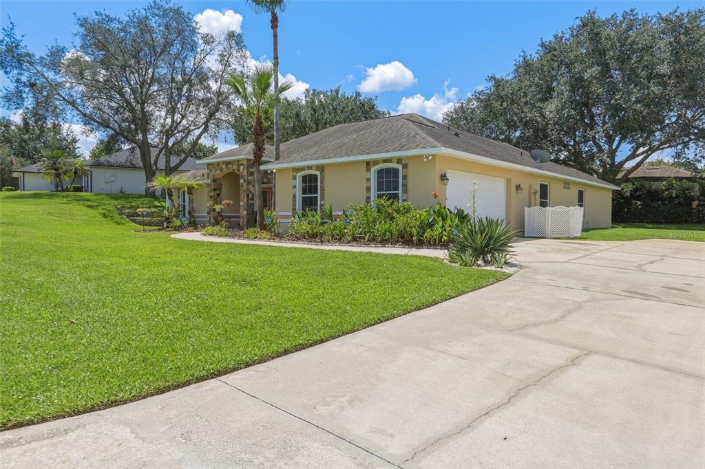 A single-story house with a tan exterior, stone accents, and a concrete driveway — 11340 ALAMEDA SANDRA DRIVE, CLERMONT, FL