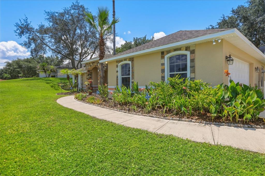 A single-story house with a beige stucco exterior, stone accents, and a landscaped front walkway — 11340 ALAMEDA SANDRA DRIVE, CLERMONT, FL