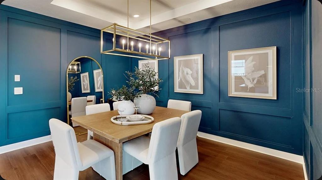 A dining room features dark blue paneled walls, a wooden table, and a gold light fixture — 11234 SILVER TRUMPET LOOP, WINTER GARDEN, FL