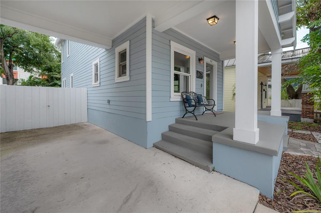 A light blue house features a covered porch with concrete steps and a metal bench — 412 E AMELIA AVENUE, TAMPA, FL
