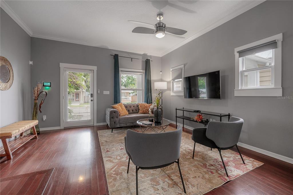 A living room features gray walls, hardwood floors, a ceiling fan, and a mounted television — 412 E AMELIA AVENUE, TAMPA, FL