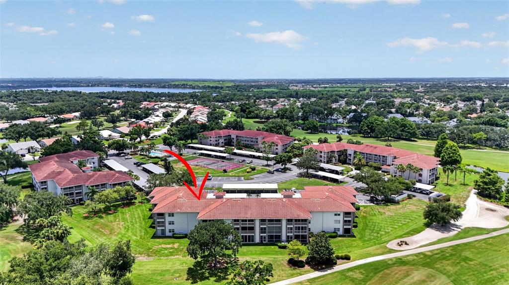 An aerial view shows a multi-story apartment building with a red tile roof — 6505 STONE RIVER ROAD UNIT 308, BRADENTON, FL