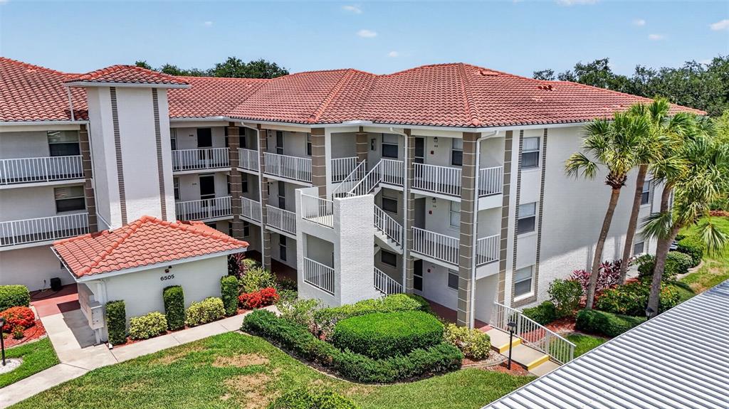 An exterior view of a multi-story apartment building with a red tile roof — 6505 STONE RIVER ROAD UNIT 308, BRADENTON, FL