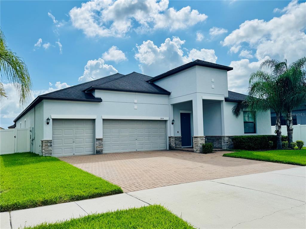 A single-story house with a three-car garage, stone accents, and a paved driveway — 11614 SUNBURST MARBLE ROAD, RIVERVIEW, FL
