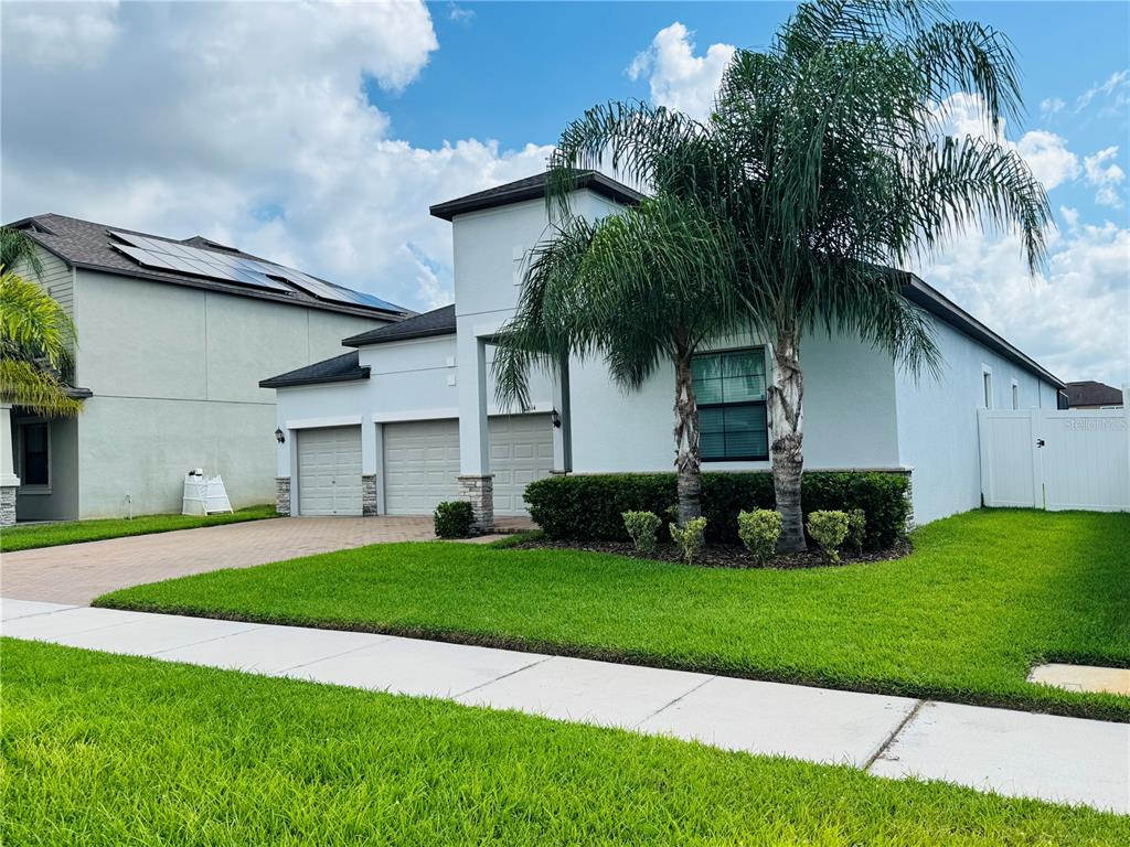 A single-story house with a three-car garage, a palm tree, and a white fence — 11614 SUNBURST MARBLE ROAD, RIVERVIEW, FL