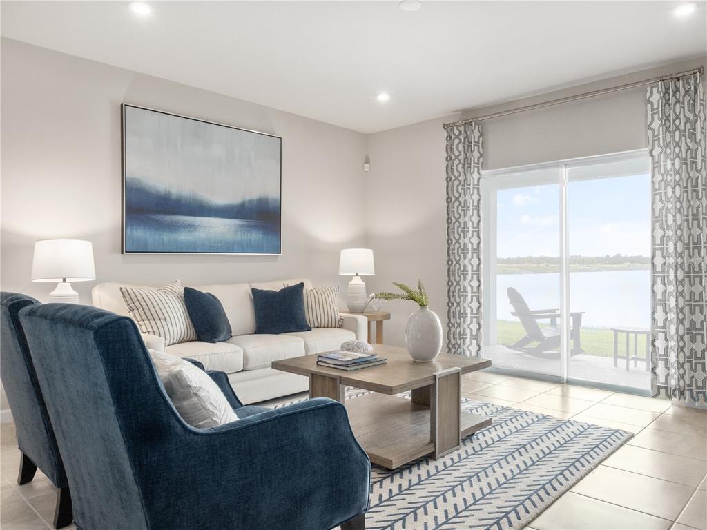 A living room features a white sofa, blue armchairs, a coffee table, and sliding glass doors — 1258 TURTLE ISLAND ROAD, LADY LAKE, FL