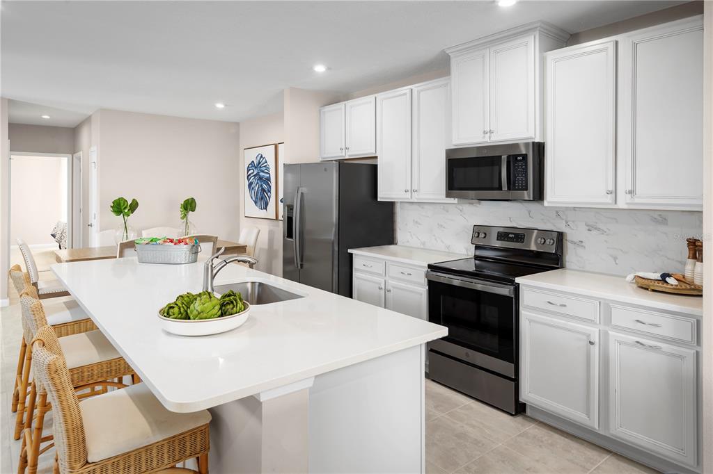 A modern kitchen features white cabinets, stainless steel appliances, and a large central island — 1258 TURTLE ISLAND ROAD, LADY LAKE, FL