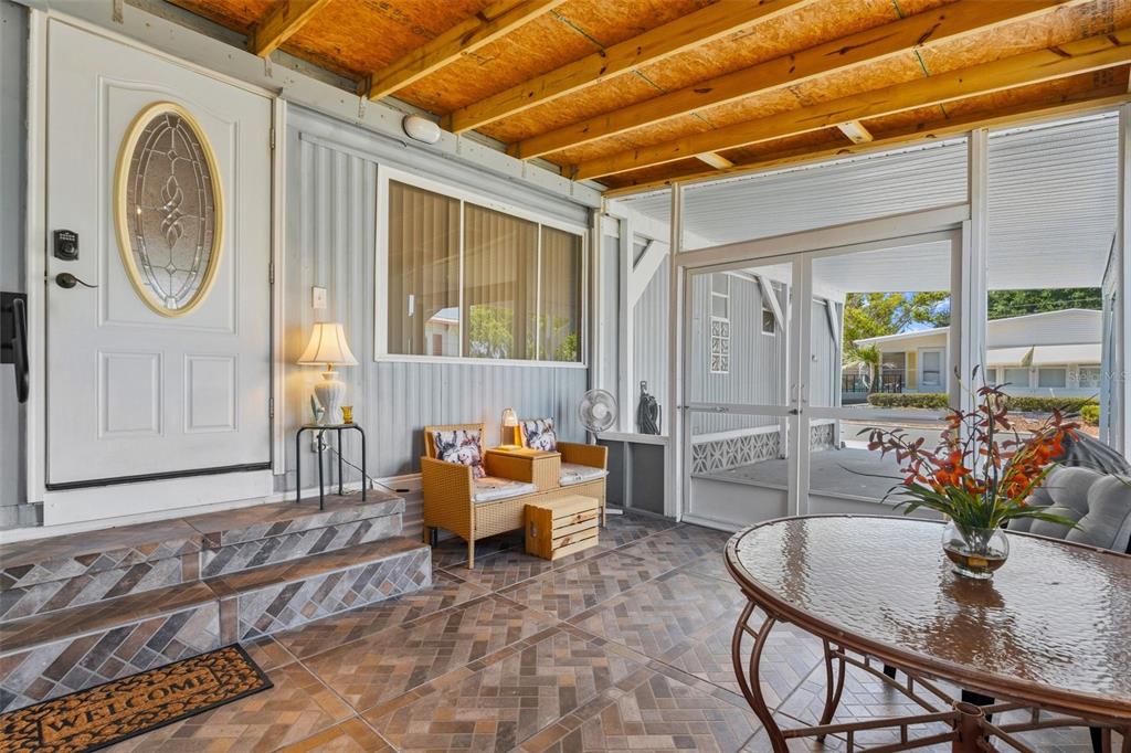 A covered porch features tiled flooring, a glass-paneled door, and outdoor furniture — 970 JOLANDA CIRCLE, VENICE, FL