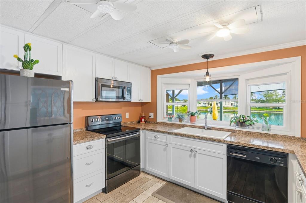 A kitchen with white cabinets, stainless steel appliances, granite countertops, and a view of water — 970 JOLANDA CIRCLE, VENICE, FL