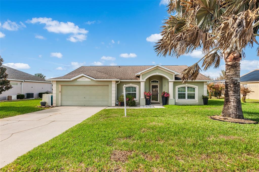 A single-story house with a light green exterior, a two-car garage, and a palm tree — 4367 DINNER LAKE BOULEVARD, LAKE WALES, FL