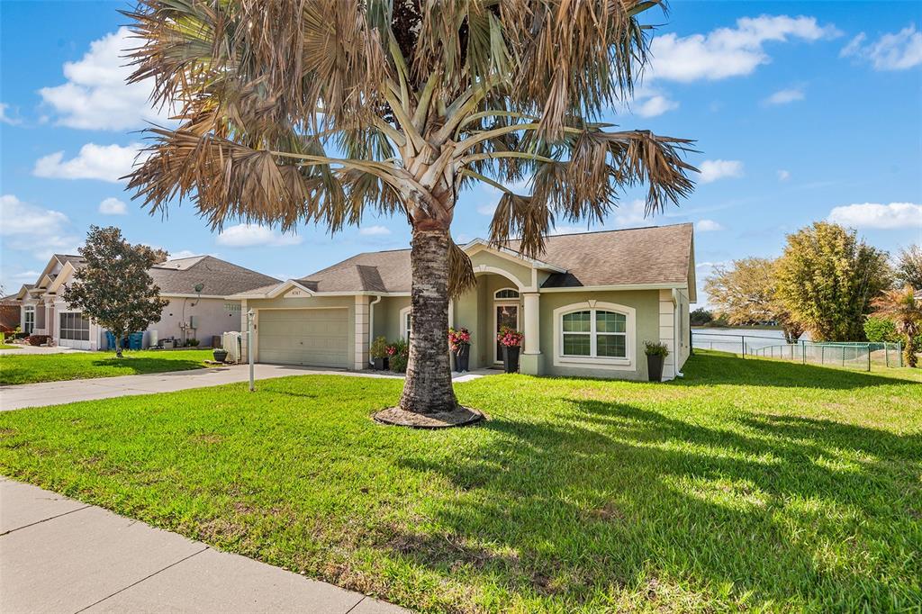 A single-story house with a palm tree in the front yard and a lake view — 4367 DINNER LAKE BOULEVARD, LAKE WALES, FL
