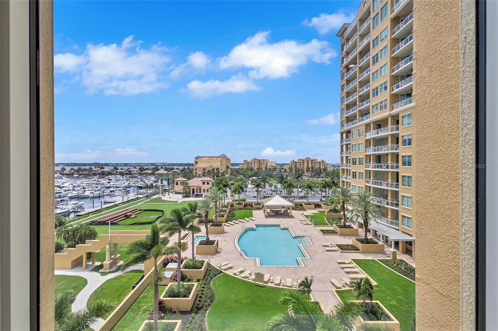 An elevated view shows a swimming pool, landscaped grounds, a marina, and a tall building — 140 RIVIERA DUNES WAY UNIT 503, PALMETTO, FL