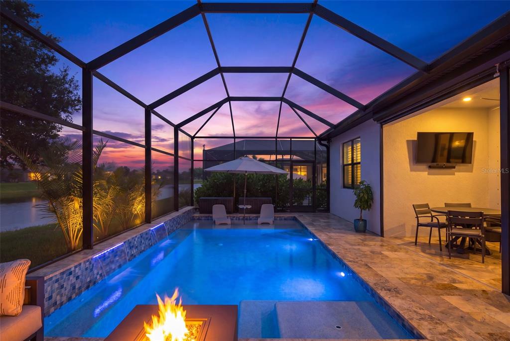A screened-in patio features a swimming pool, a fire pit, and outdoor dining furniture — 704 PINTAIL COVE, BRADENTON, FL