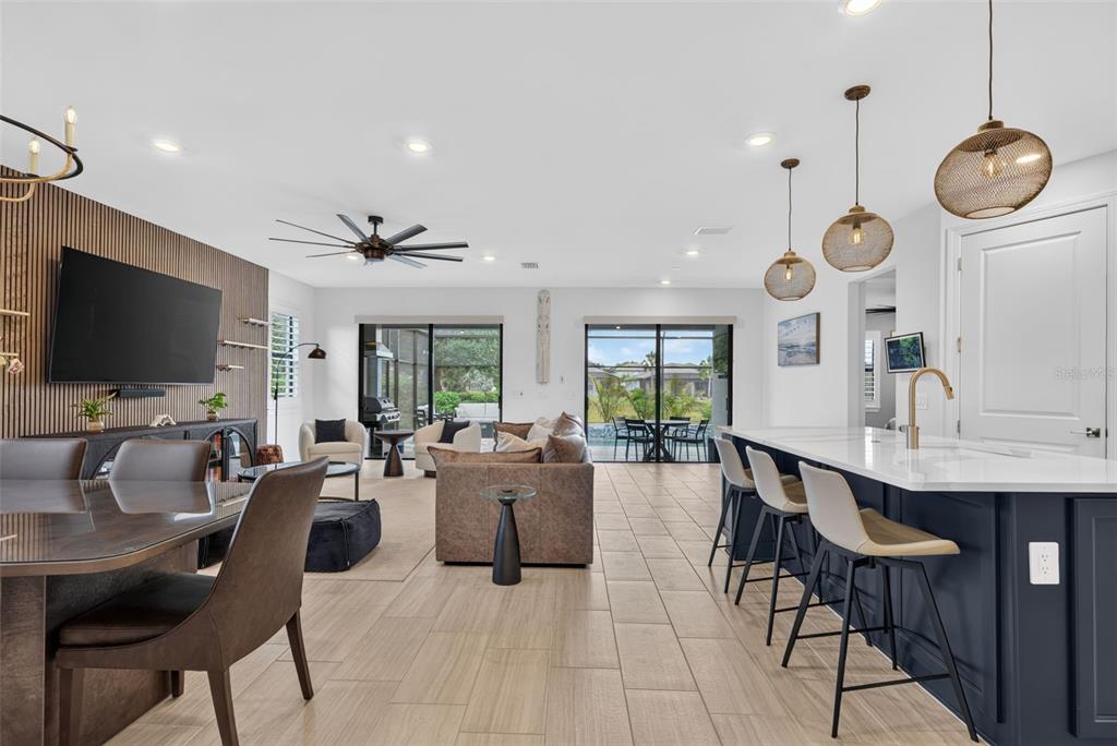 An open-concept living area features a kitchen island, dining space, and sliding glass patio doors — 704 PINTAIL COVE, BRADENTON, FL