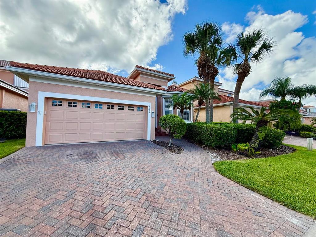 A single-story house with a beige stucco exterior, a tiled roof, and a brick paver driveway — 1605 SAND KEY ESTATES COURT, CLEARWATER, FL
