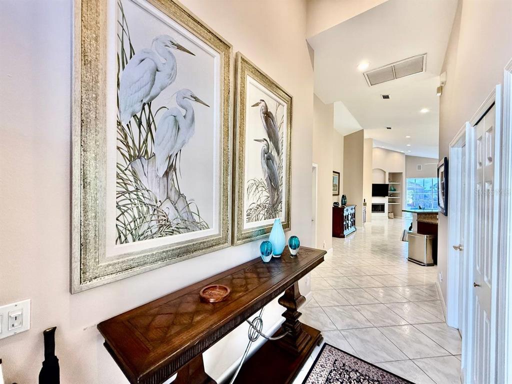 A hallway features a wooden console table, two heron wall prints, and tile flooring — 1605 SAND KEY ESTATES COURT, CLEARWATER, FL