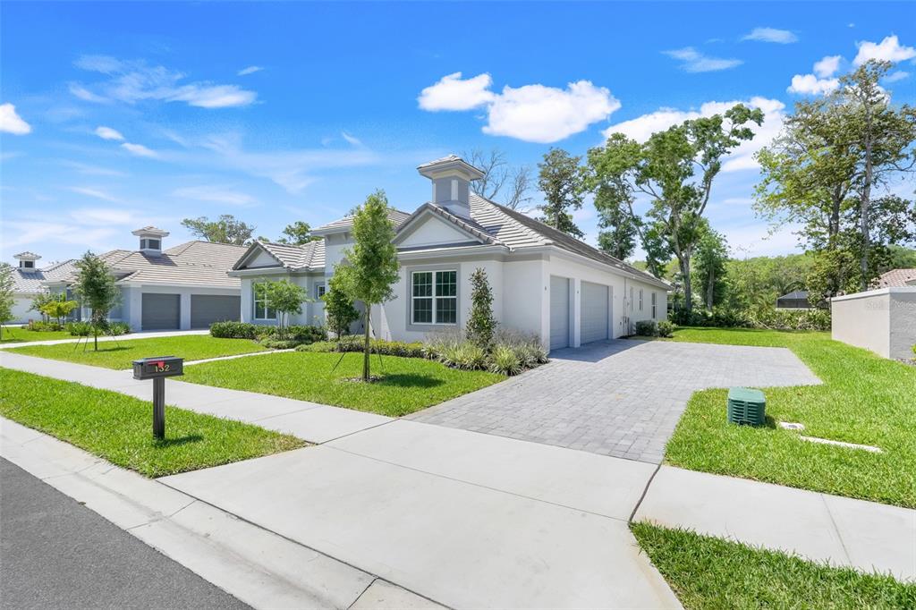 A white single-story house with a gray tile roof and a paved driveway — 132 NEW LEATHERWOOD DRIVE, PALM COAST, FL