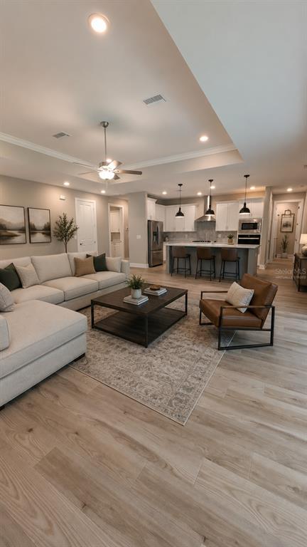 An open-concept living room and kitchen feature light wood flooring, neutral furniture, and recessed lighting — 5934 SUMMIT VIEW DRIVE, BROOKSVILLE, FL