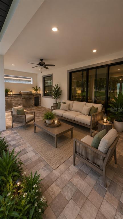 A covered outdoor patio features a seating area, a built-in grill, and stone flooring — 5934 SUMMIT VIEW DRIVE, BROOKSVILLE, FL
