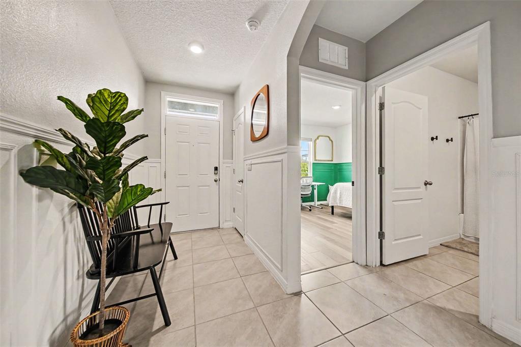 A bright entryway features tile flooring, white wainscoting, a black bench, and two doorways — 6708 ALDER RD, HARMONY, FL