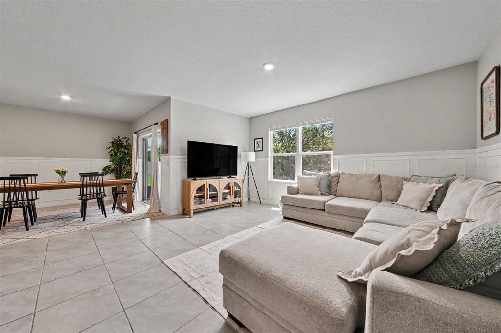 A living room and dining area feature tile floors, white wainscoting, and a sectional sofa — 6708 ALDER RD, HARMONY, FL