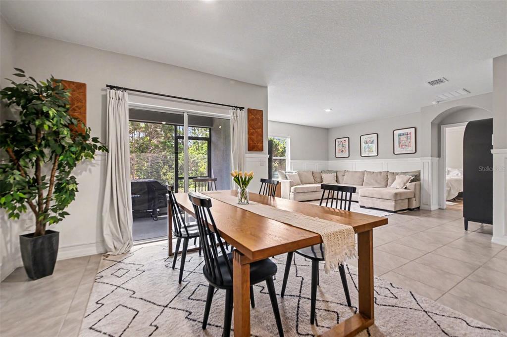 A dining area with a wooden table and chairs opens into a living room space — 6708 ALDER RD, HARMONY, FL