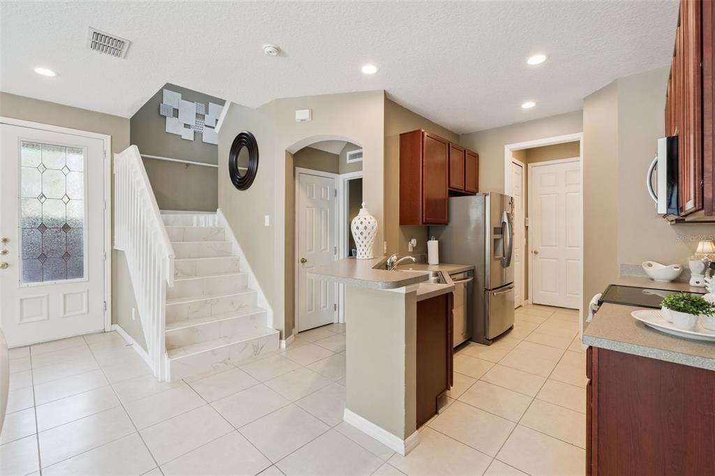 A kitchen with tile flooring, dark wood cabinets, and a staircase leading to an upper level — 7506 CRANES CREEK COURT UNIT 30, WINTER PARK, FL