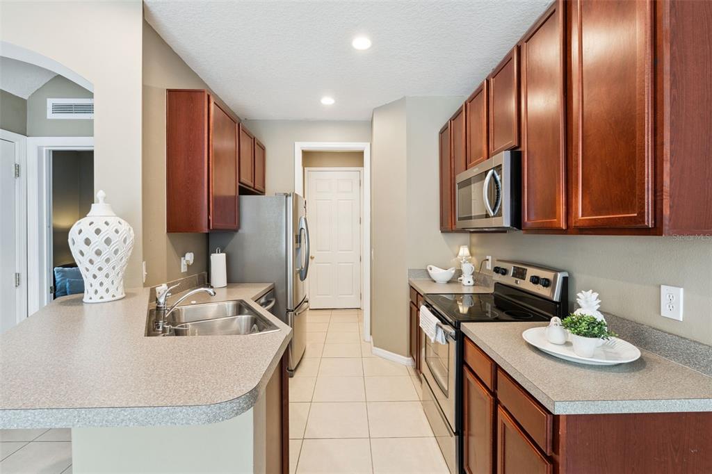 A kitchen features dark wood cabinets, stainless steel appliances, and a gray laminate countertop — 7506 CRANES CREEK COURT UNIT 30, WINTER PARK, FL