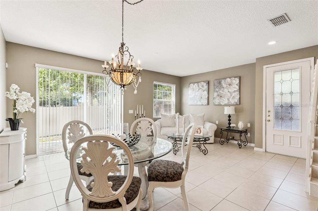 A dining area with a glass table and chandelier sits adjacent to a living space — 7506 CRANES CREEK COURT UNIT 30, WINTER PARK, FL