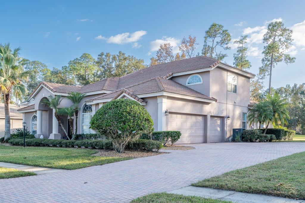 A two-story house with a tiled roof, beige stucco exterior, and a paved driveway — 1084 SHADOWMOSS CIRCLE, LAKE MARY, FL