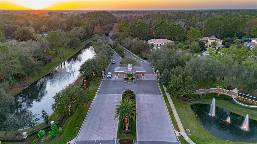 An aerial view of a gated community entrance with a fountain and landscaped road — 1084 SHADOWMOSS CIRCLE, LAKE MARY, FL