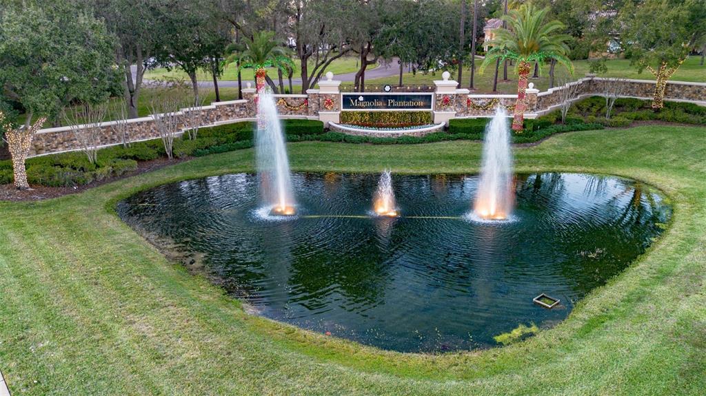 An aerial view of a pond with three fountains in front of a gated entrance sign — 1084 SHADOWMOSS CIRCLE, LAKE MARY, FL