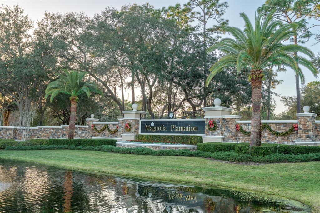 A stone entrance sign for Magnolia Plantation sits behind a pond with palm trees — 1084 SHADOWMOSS CIRCLE, LAKE MARY, FL