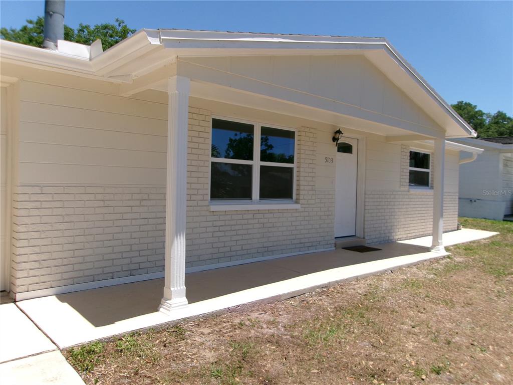 The exterior of a single-story house features white brick, siding, and a covered front porch — 5103 VALIMOR DRIVE, HOLIDAY, FL