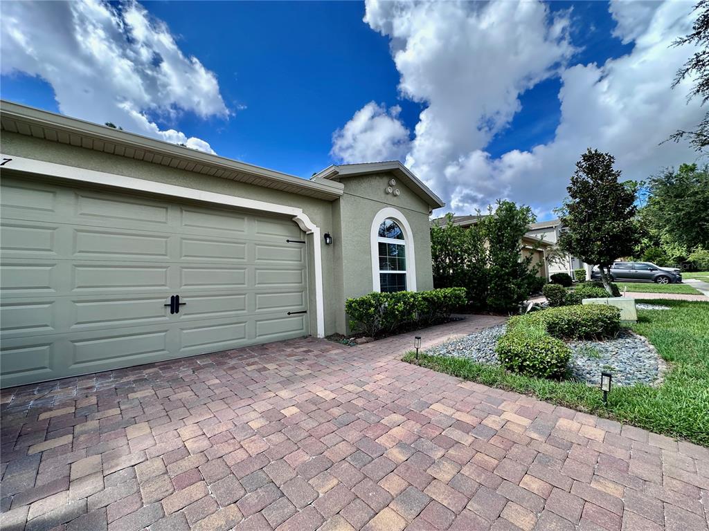 A light green house exterior features a two-car garage and a paved driveway — 1557 AMBER LEAF CIRCLE, OCOEE, FL