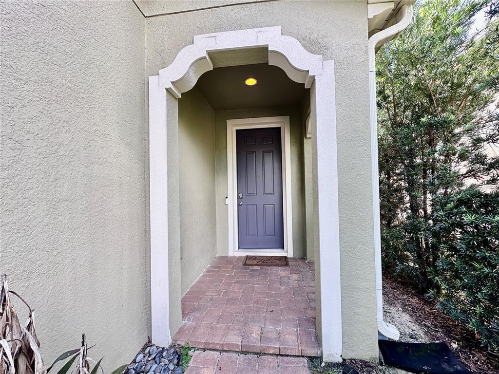 A front entryway features a purple door, a brick floor, and a decorative arched frame — 1557 AMBER LEAF CIRCLE, OCOEE, FL