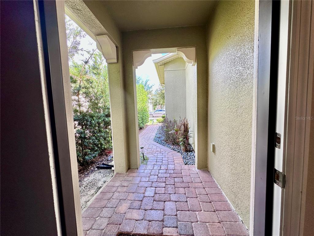 A view from a doorway looking out onto a brick-paved walkway and covered entryway — 1557 AMBER LEAF CIRCLE, OCOEE, FL