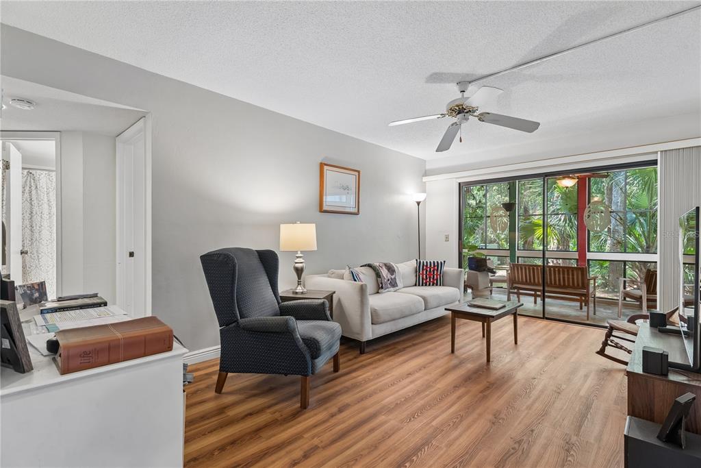 A living room features wood-look flooring, a ceiling fan, a sofa, and a sliding glass door — 35 FAIRWAYS CIRCLE UNIT 35, PALM COAST, FL